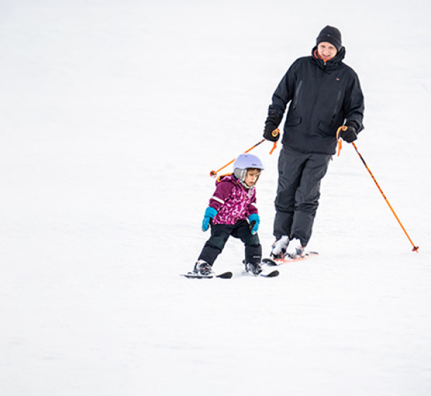 WinSport Winter Season Pass dad and child skiing down the hill v3