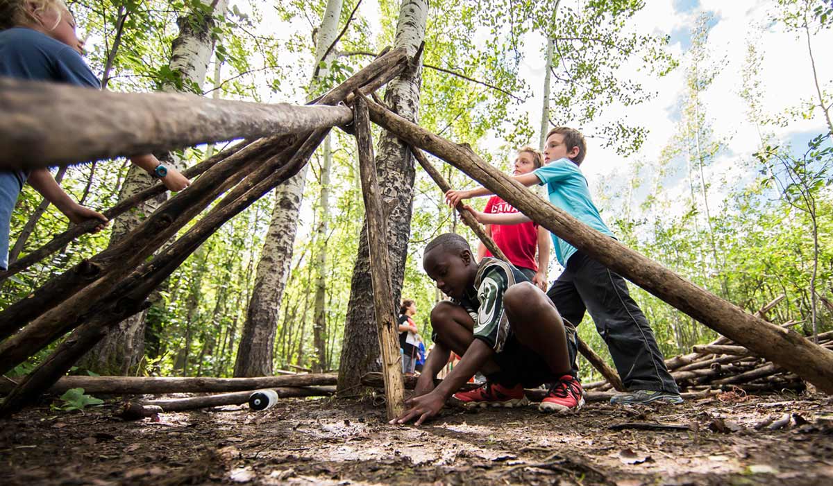 Group of children learning how to build a hut in outdoor adventure programs