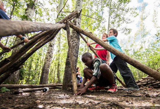 Group of children learning how to build a hut in outdoor adventure programs