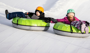 Brother and sister sliding down the Servus Tube Park at WinSport while holding hands