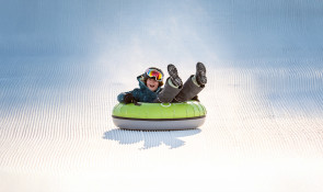 Excited child gaining speed down the Servus Tube Park at WinSport