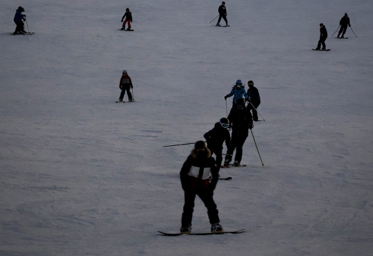 Group of skiiers and snowboarders working their way down the winter hill at winsport