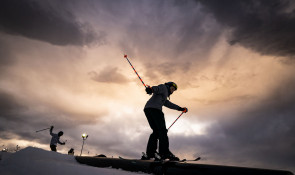 Skier learning how to hit a rail at the WinSport terrain park
