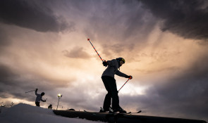 Skier learning how to hit a rail at the WinSport terrain park