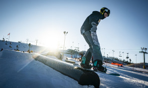 Snowboarder exiting a rail at the WinSport Terrain Park