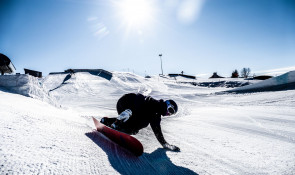 Snowboarder going down the terrain park at WinSport