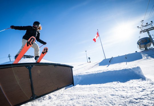 Female skier at WinSport doing freestyle skiing trick on rail