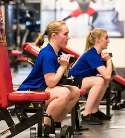Two athletes training together doing goblet squats in the performance training centre