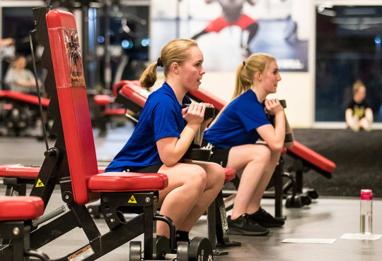 Two athletes training together doing goblet squats in the performance training centre