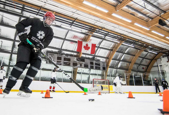 Adult rounding a corner with a hockey puck at WinSport
