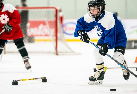 Boy ready to pass hockey puck after completing a drill at WinSport