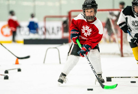 Close up of young boy skating through a hockey drill with a puck on his stick
