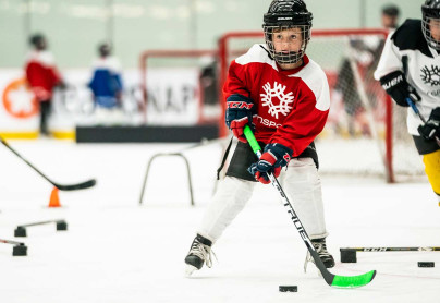 Close up of young boy skating through a hockey drill with a puck on his stick