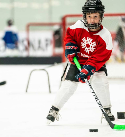 Close up of young boy skating through a hockey drill with a puck on his stick