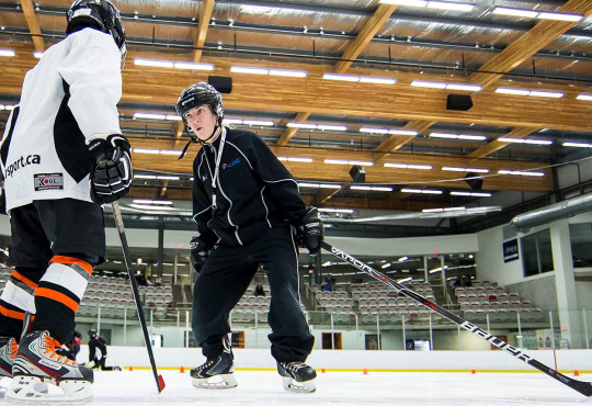 Instructor giving tips to young boy power skating
