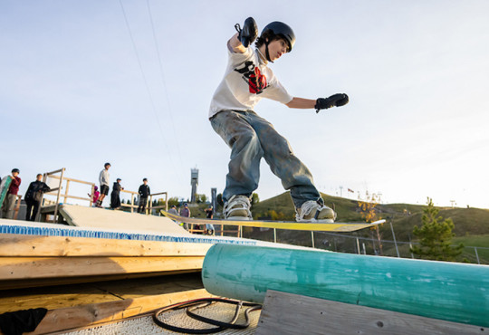 Freestyle participant going off jump towards the WinSport DrySlope rail