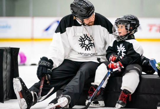 Winsport DevelopmentHockeyU7 coachsitswithayoungplayer