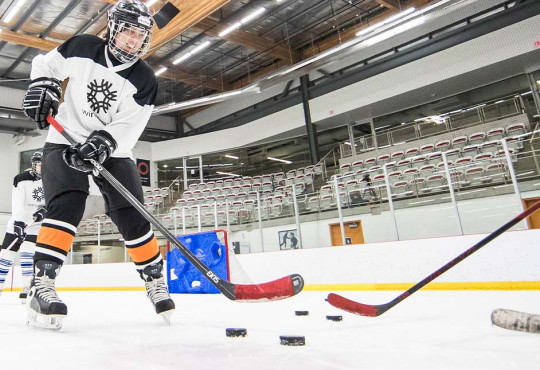 Group of women stick handling pucks during a WinSport Women Discover Hockey program