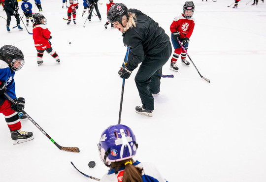 Group of hockey players surrounding the crease learning to play hockey