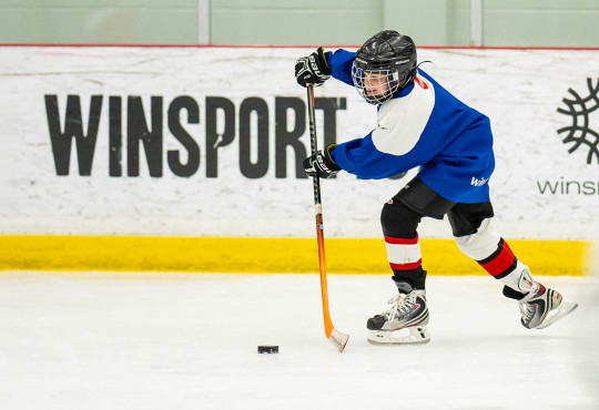 Young hockey camper passing the puck during a summer camp