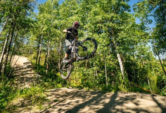 Mountain biker safely going off a well groomed dirt jump at winsport