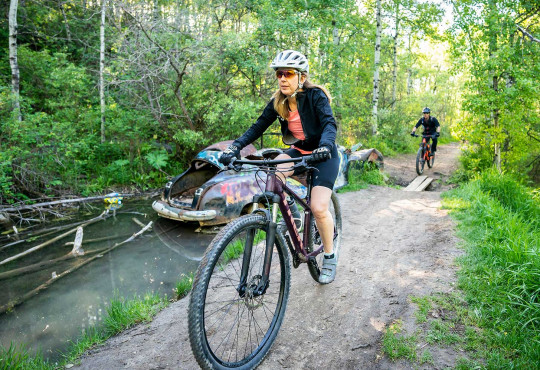 Adult female riding her bike through a trail at Canada Olympic Park