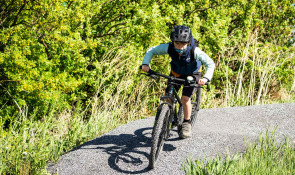 Boy riding his bike around a berm at the mountain bike skills park at WinSport