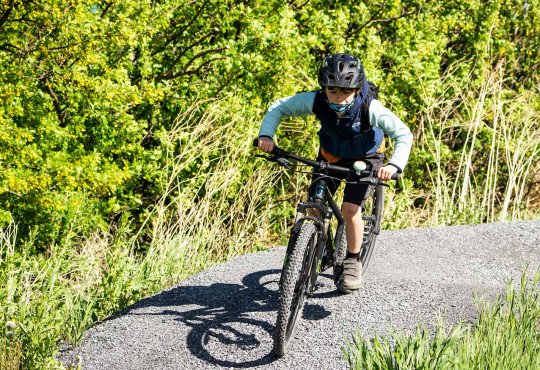 Boy riding his bike around a berm at the mountain bike skills park at WinSport