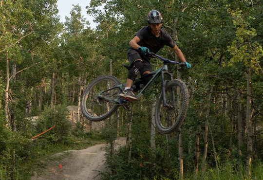 Mountain biker getting some air over dirt jumps on the downhill course at winsport