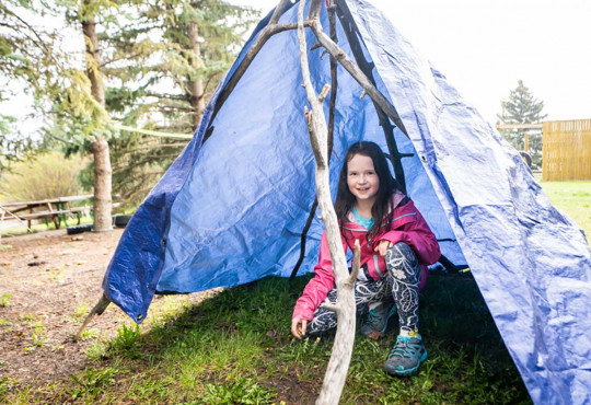 Girl taking shelter in tent during outdoor adventure programming