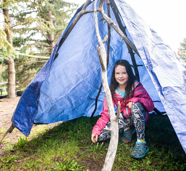 Girl taking shelter in tent during outdoor adventure programming