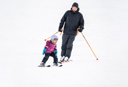 Father and daughter skiing down a hill during winter at winsport
