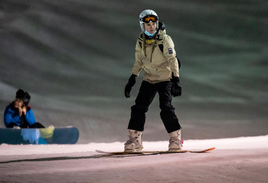 Female rider going down snowboard hill