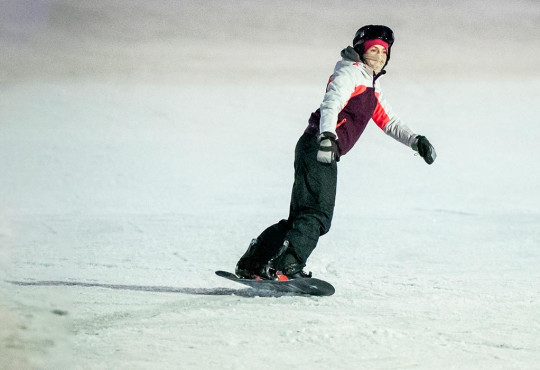 Female snowboarding at night down the ski hill at winsport