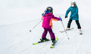 One on one instructor with small child learning how to ski