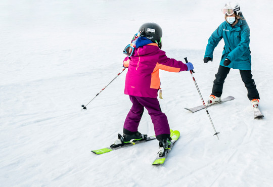 One on one instructor with small child learning how to ski