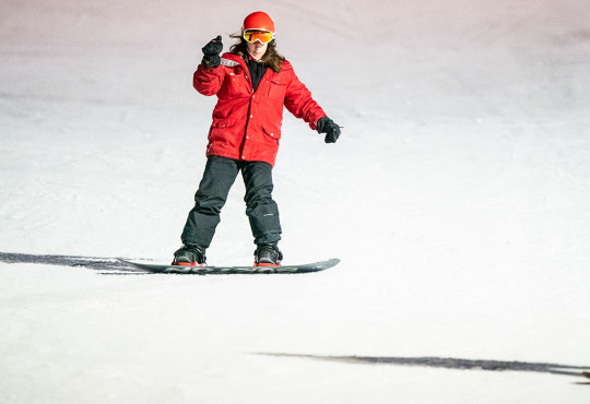 Two adults snowboarding down the ski hill at winsport