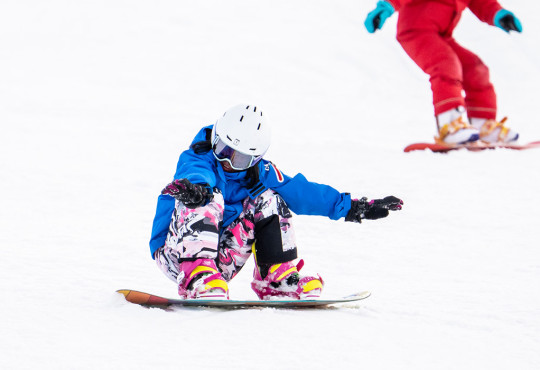 Young girl holding balance on snowboard while going down the hill at winsport