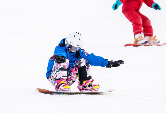 Young girl holding balance on snowboard while going down the hill at winsport