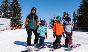 Family learning how to snowboard on WinSports beginner hill