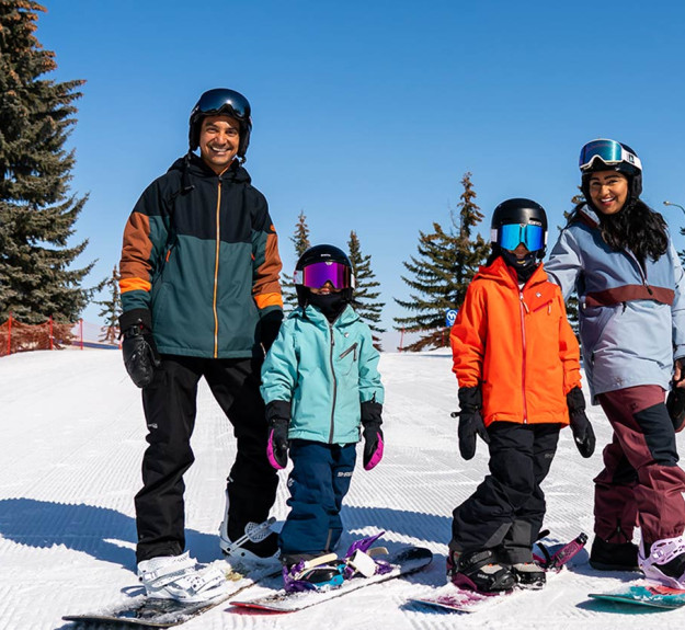 Family learning how to snowboard on WinSports beginner hill
