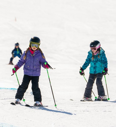 Two first time skiiers learning how to ski down the WinSport hil