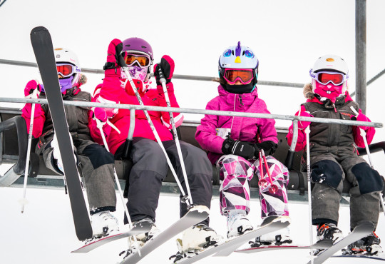 Youth ski girls taking a ride up the chairlift at WinSport