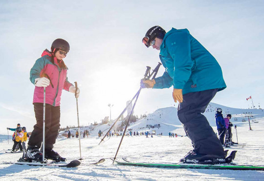 Instructor teaching a new skiier the basics while standing on snow copy
