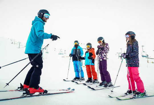 Intructor giving instruction to a group of children learning to ski