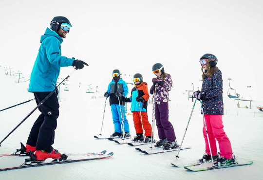 Intructor giving instruction to a group of children learning to ski