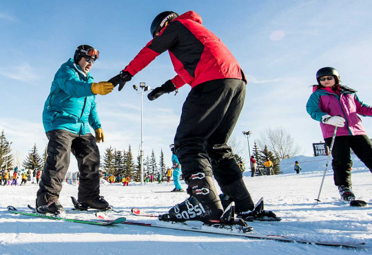 Private lesson instructor teaching new skiiers how to stand on snow at winsport copy