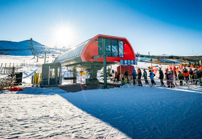 Skiers and snowboarders line up at the chairlift to go up the hill at winsport