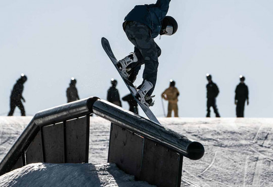 Snowboarder sliding on a rail in the terrain park at winsport copy