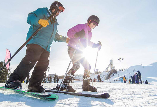WinSport Snow School instructor guiding a beginner skiier down the rabbit hill copy